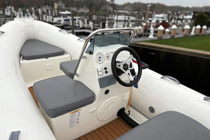 Slide: The Image of 2022 Brig Falcon Tender 420 boat interior with steering wheel and seating, docked at marina. - 6