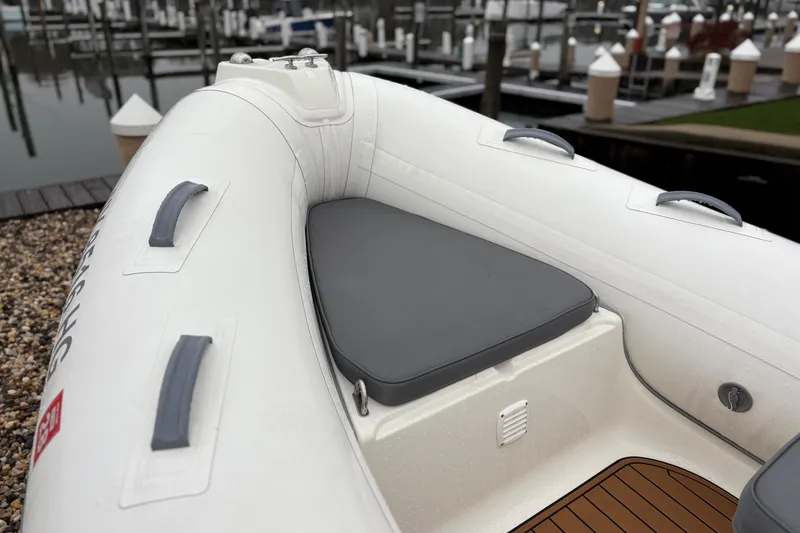 Slide: The Image of 2022 Brig Falcon Tender 420 boat with cushioned seating, docked at a marina. - 9