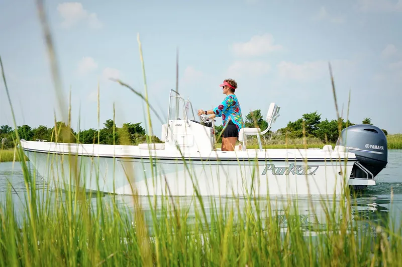 Slide: The Image of Manufacturer Provided Image: 2018 Parker 1801 Center Console boat on a calm lake with a person steering. - 2