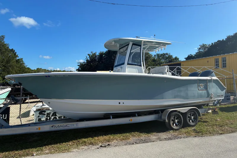 The Image of 2019 Sea Hunt Gamefish 27 boat on trailer, parked outdoors under clear sky. - 1