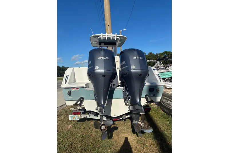 Slide: The Image of 2019 Sea Hunt Gamefish 27 with dual Yamaha 250 engines, parked on grass. - 2