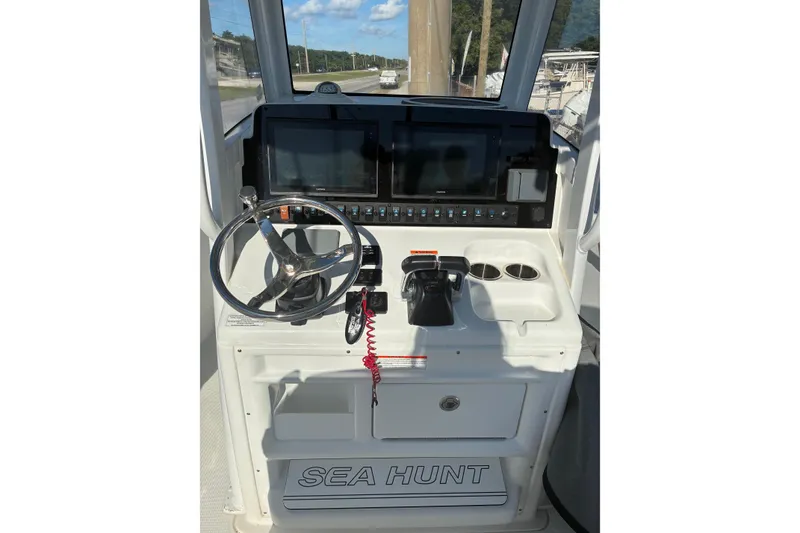 Slide: The Image of 2019 Sea Hunt Gamefish 27 helm with steering wheel, controls, and dual displays. - 5
