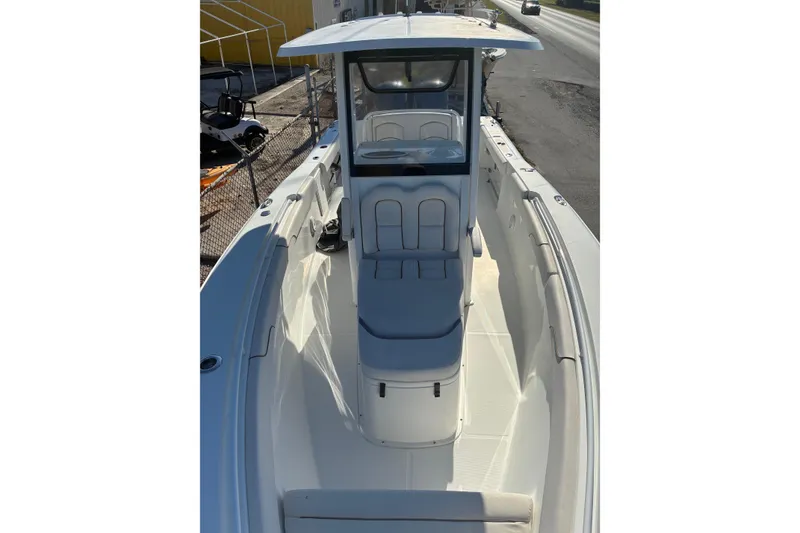 Slide: The Image of 2019 Sea Hunt Gamefish 27 boat with spacious deck and seating, docked near a road. - 7