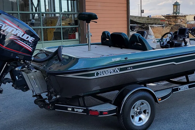 Slide: The Image of 2008 Champion 183 CX boat with Evinrude motor, parked outside a garage. - 4