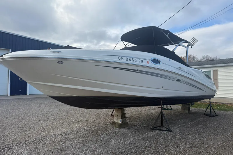 Slide: The Image of 2013 Sea Ray 300 Sundeck boat on stands, white hull, black canopy, outdoor setting. - 32