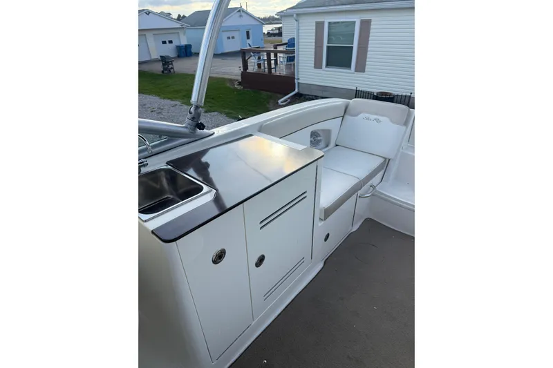Slide: The Image of 2013 Sea Ray 300 Sundeck interior with sink, storage, and seating area. - 5