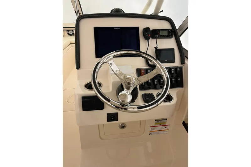 Slide: The Image of 2024 Grady-White Freedom 235 helm with steering wheel and navigation controls. - 6