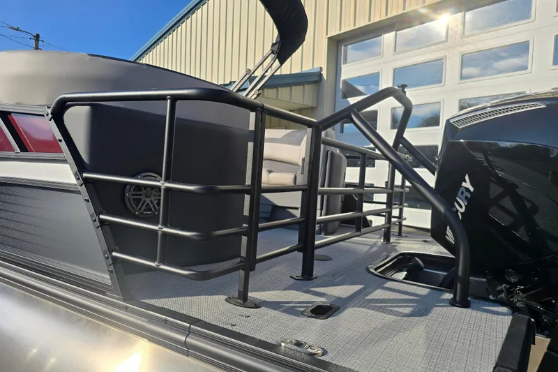 Slide: The Image of 2024 Sylvan L3 LZ pontoon boat with Mercury engine, docked near a garage. - 4