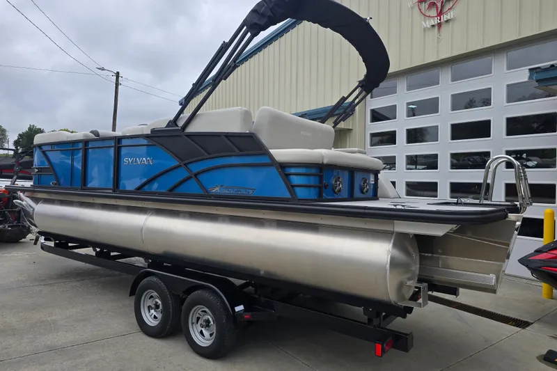 Slide: The Image of 2024 Sylvan Mirage X X5 CLZ pontoon boat on trailer, blue and silver design. - 2