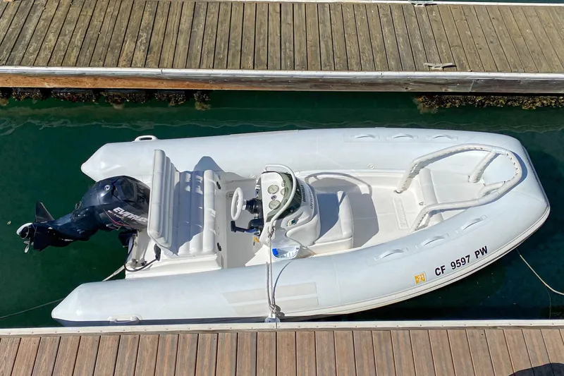 Slide: The Image of Aerial view of a white inflatable boat docked, featuring an Evinrude outboard motor. - 54
