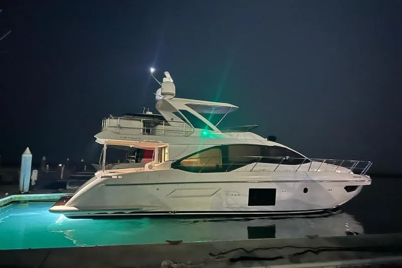 Slide: The Image of Luxurious 2021 Azimut 55 yacht docked at night, illuminated by green lights. - 0