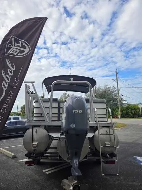 Slide: The Image of 2020 Veranda VTX22RC pontoon boat with 150 HP motor, parked outdoors under a cloudy sky. - 12