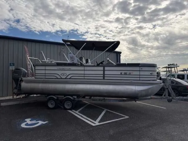 Slide: The Image of 2020 Veranda VTX22RC pontoon boat on trailer, parked in a lot under cloudy sky. - 2