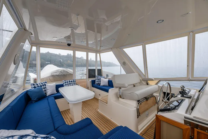 Slide: The Image of Luxurious 2026 Fleming 55 Pilothouse interior with blue seating, helm, and panoramic windows. - 44