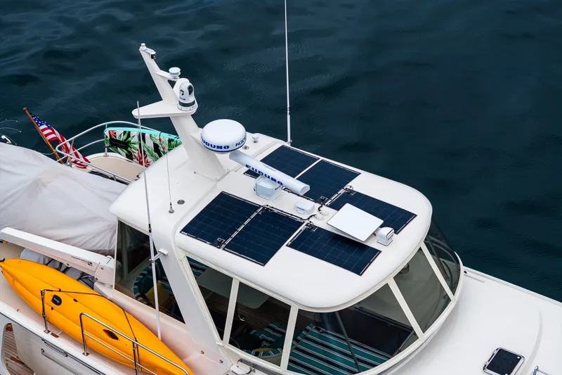 Slide: The Image of Fleming 55 Pilothouse 2026 with solar panels and kayak on deck, cruising on water. - 9