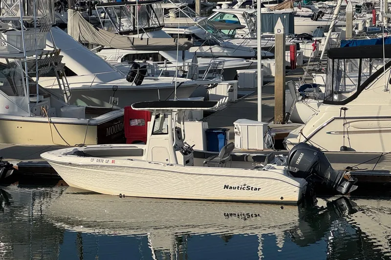 Slide: The Image of 2023 NauticStar 242L Offshore boat interior with seating and fishing rod holders. - 2