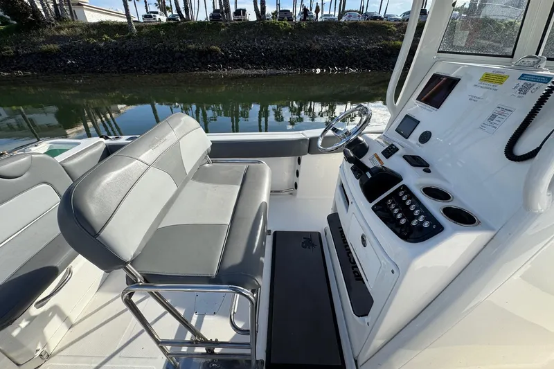 Slide: The Image of 2023 NauticStar 242L Offshore boat interior with steering console, docked by calm waters. - 22