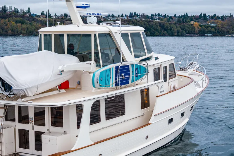 Slide: The Image of 2026 Fleming 55 Pilothouse yacht cruising on a serene lake with lush shoreline. - 13