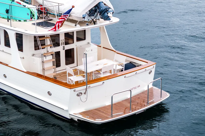 Slide: The Image of 2026 Fleming 55 Pilothouse yacht with deck seating, American flag, and ocean backdrop. - 15