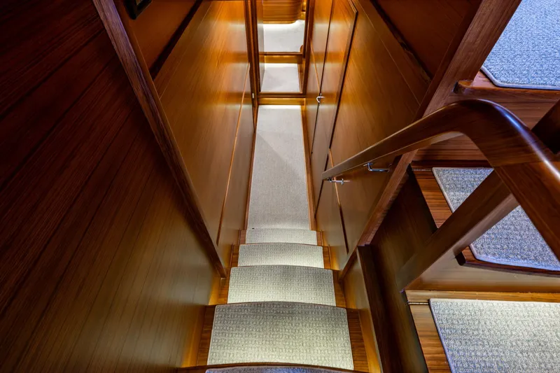 Slide: The Image of Staircase inside 2026 Fleming 55 Pilothouse yacht with wooden finish and carpeted steps. - 45