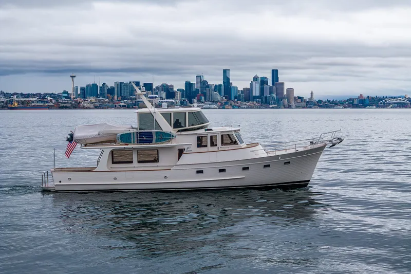 Slide: The Image of 2026 Fleming 55 Pilothouse yacht cruising near city skyline under cloudy skies. - 11