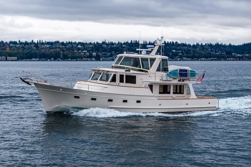 Slide: The Image of 2026 Fleming 55 Pilothouse yacht cruising on a scenic lake under cloudy skies. - 9