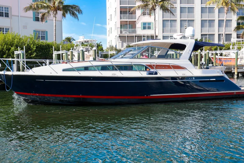 The Image of 2004 Chris-Craft Roamer 40 yacht docked in a marina, surrounded by palm trees. - 0
