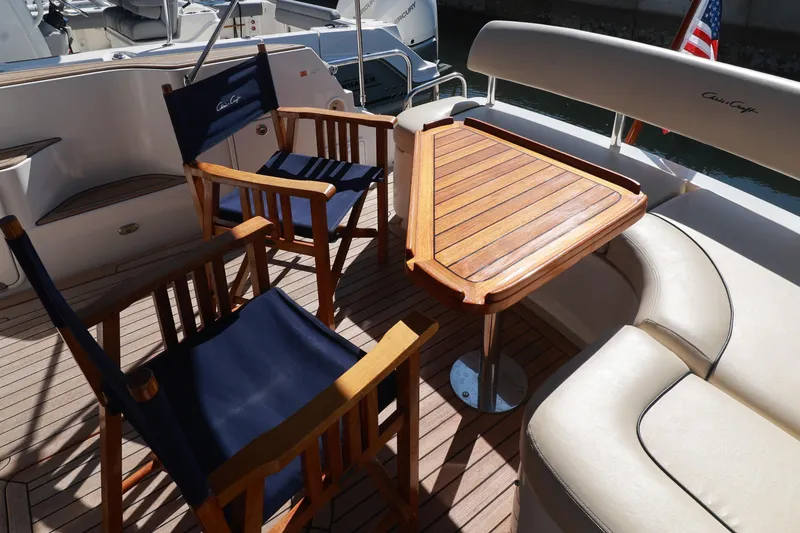 Slide: The Image of Luxury seating area on 2004 Chris-Craft Roamer 40 yacht with wooden table and chairs. - 17