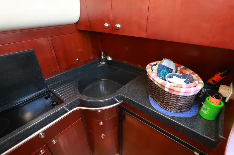 Slide: The Image of 2004 Chris-Craft Roamer 40 yacht kitchen with wooden cabinets and black countertop. - 25