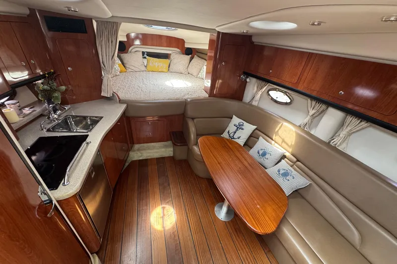 Slide: The Image of 2008 Crownline 340 CR cabin interior with kitchenette, seating, and cozy sleeping area. - 12