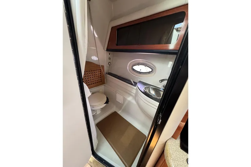 Slide: The Image of 2008 Crownline 340 CR boat bathroom with sink, toilet, and porthole window. - 14