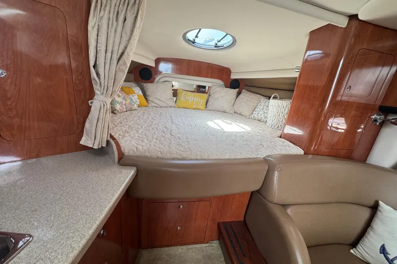 Slide: The Image of 2008 Crownline 340 CR cabin interior with cozy bed, wood finish, and natural light. - 15
