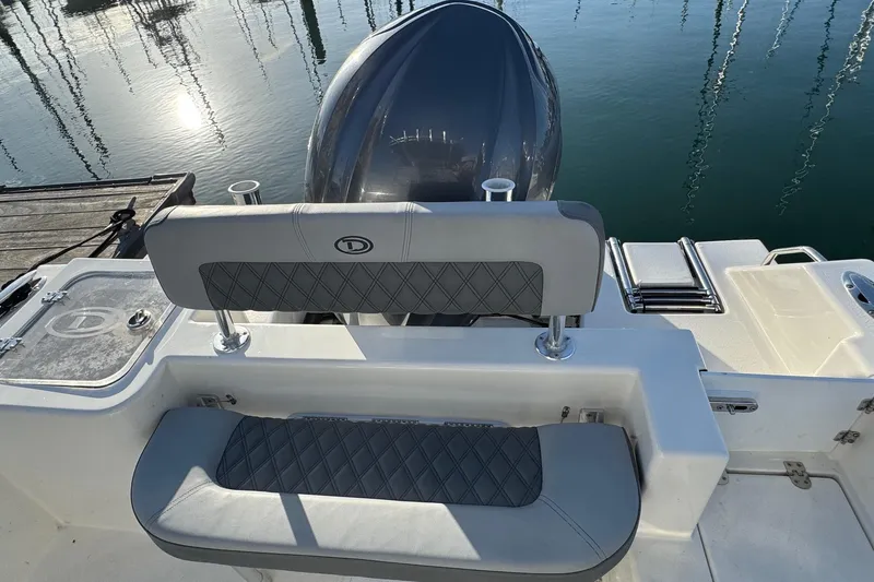 Slide: The Image of 2025 Defiance Catalina 240 boat interior with cushioned seating and outboard motor. - 35