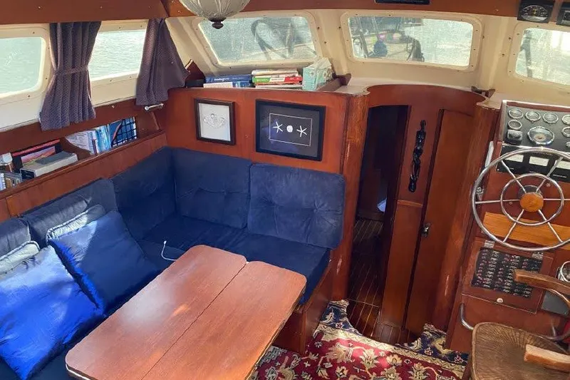 Slide: The Image of Interior of 1977 Dufour CT 12000 sailboat with cozy seating and wooden accents. - 12