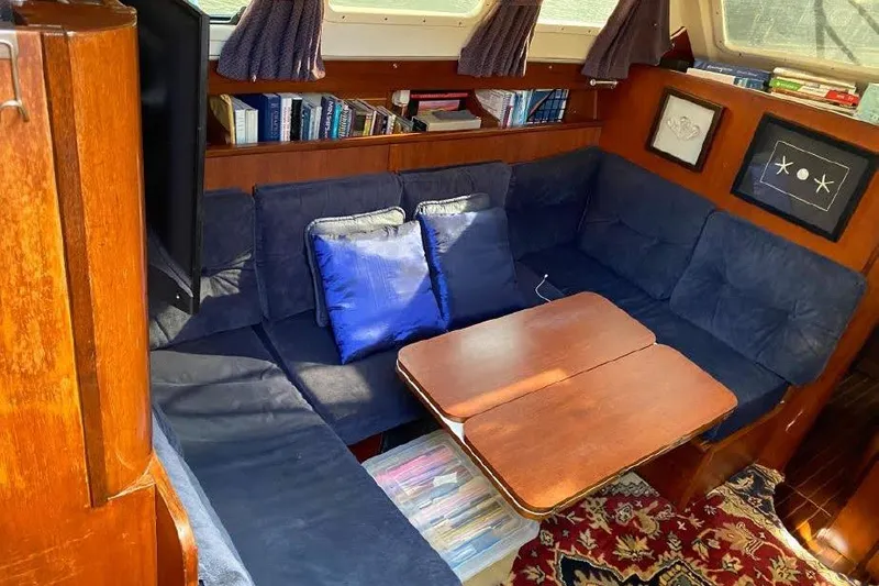 Slide: The Image of Cozy interior of 1977 Dufour CT 12000 yacht with blue seating and wooden table. - 13
