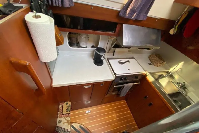 Slide: The Image of 1977 Dufour CT 12000 yacht kitchen with wooden cabinetry and modern appliances. - 15