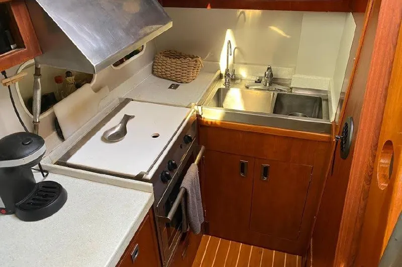 Slide: The Image of 1977 Dufour CT 12000 yacht kitchen with stove, sink, and wooden cabinetry. - 16