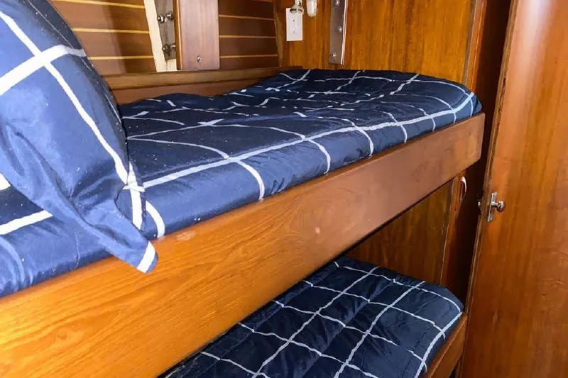 Slide: The Image of Bunk beds in a 1977 Dufour CT 12000 yacht cabin with blue checkered bedding. - 19
