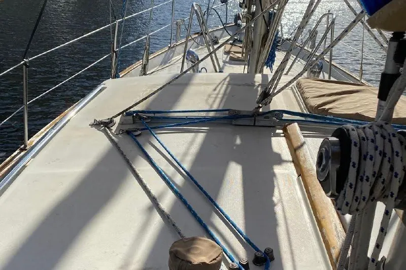 Slide: The Image of 1977 Dufour CT 12000 sailboat deck with rigging and ropes, sunlit on water. - 5