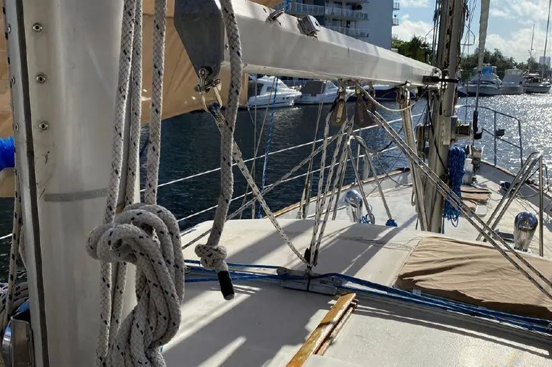 Slide: The Image of Deck view of 1977 Dufour CT 12000 sailboat with rigging and marina background. - 6