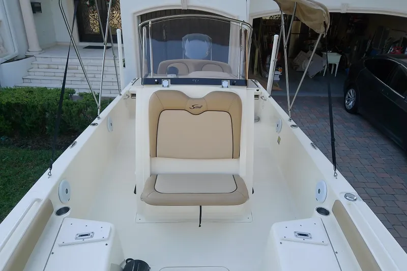 Slide: The Image of 2018 Scout 251 XSS boat interior with beige seating and console, parked in driveway. - 26