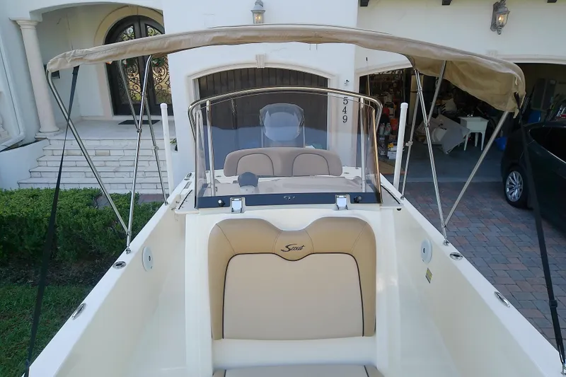 Slide: The Image of 2018 Scout 251 XSS boat with beige seating and canopy, parked in driveway. - 39