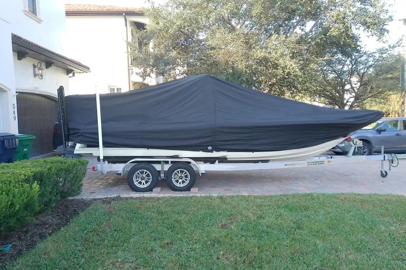 Slide: The Image of 2018 Scout 251 XSS boat covered on a trailer in a residential driveway. - 63