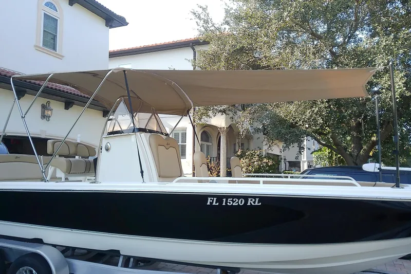 Slide: The Image of 2018 Scout 251 XSS boat with canopy, parked on trailer near house. - 68