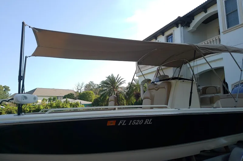 Slide: The Image of 2018 Scout 251 XSS boat with canopy, parked near a house. - 73
