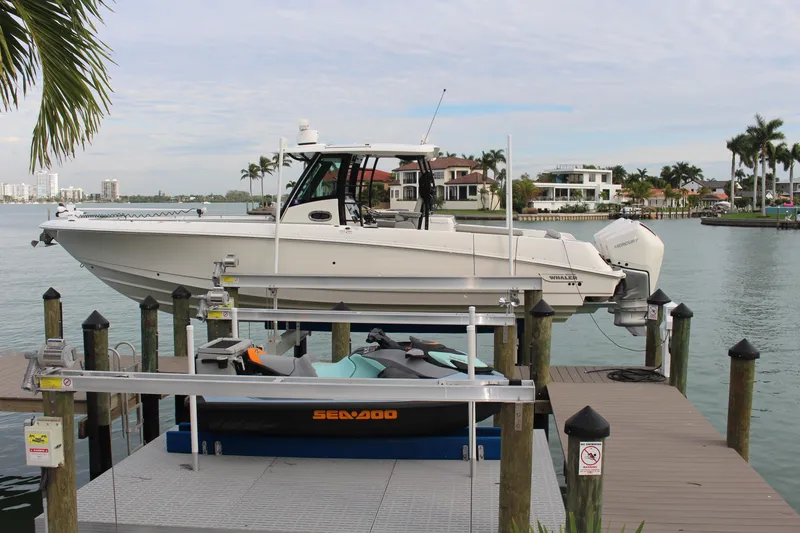 The Image of 2020 Boston Whaler 350 Outrage docked on a lift, with scenic waterfront view. - 0
