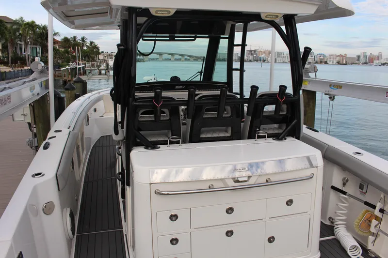 Slide: The Image of 2020 Boston Whaler 350 Outrage boat interior with seating and storage, docked by the water. - 22