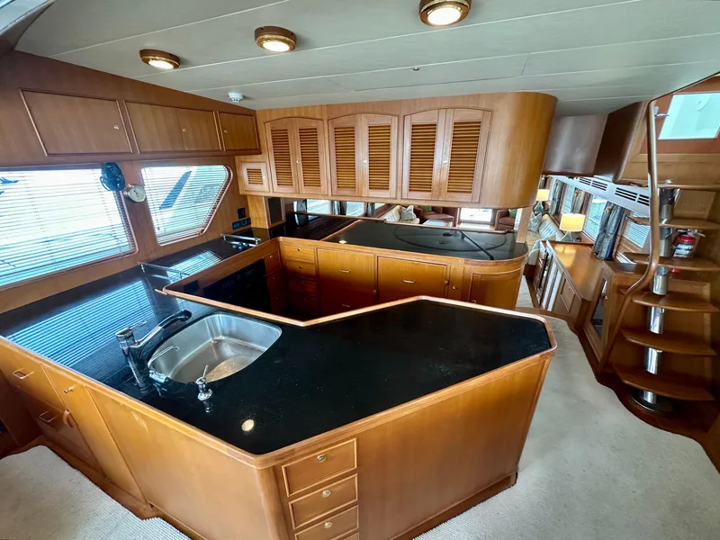 Slide: The Image of Luxurious kitchen interior of 2005 Marlow Explorer 78 yacht with wooden cabinetry and black countertops. - 19