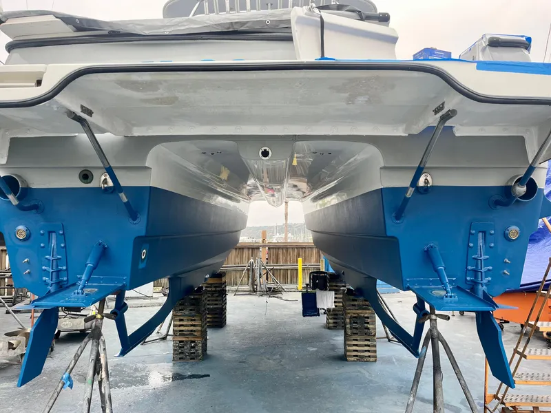 Slide: The Image of 2006 Glacier Bay 3480 Ocean Runner catamaran on dry dock, showcasing dual hulls and blue accents. - 11