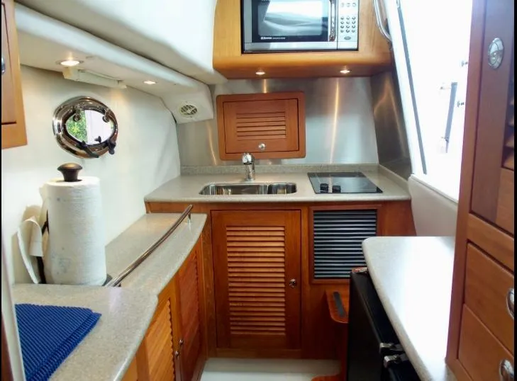 Slide: The Image of Compact kitchen in 2006 Glacier Bay 3480 Ocean Runner boat with sink, stove, and microwave. - 26
